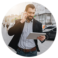 Businessman walking in city on tablet and phone