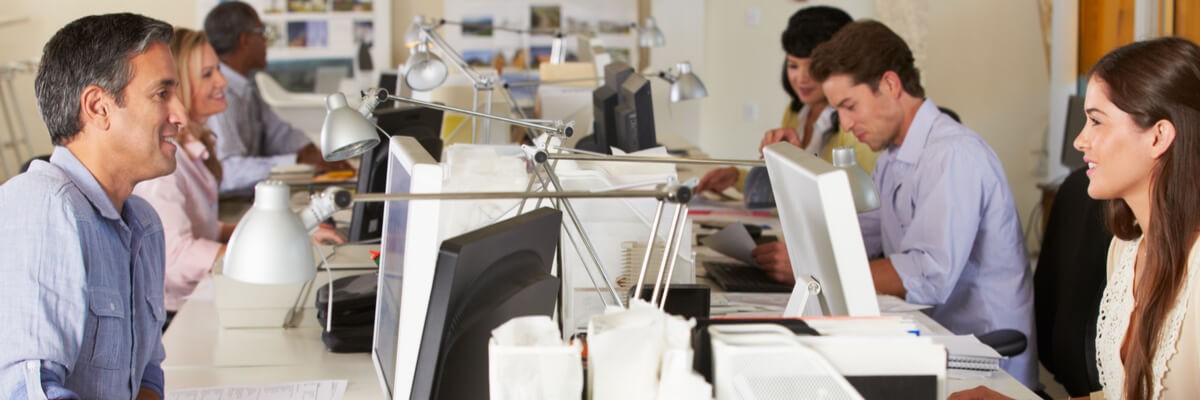 A group of people in an office all happily working on their computing service