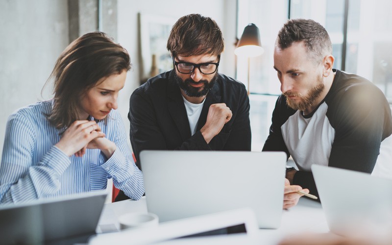 See how IT leaders are leveraging modernization as a strategy for business growth Group of IT leaders reading report about business strategy on laptop computer