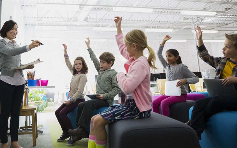 Classroom of children and teacher learning while using laptop and tablet devices