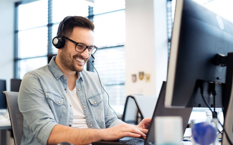 man-smiling-using-headset-device-and-notebook