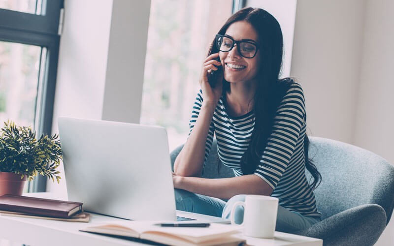 woman-smiling-on-mobile-device-while-working