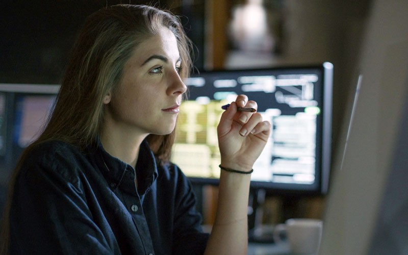 Programmer looks through code on desktop at night