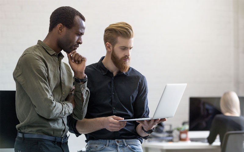 You’ll get the expertise to mitigate risk during the audit lifecycle Two businessmen standing holding laptop computer